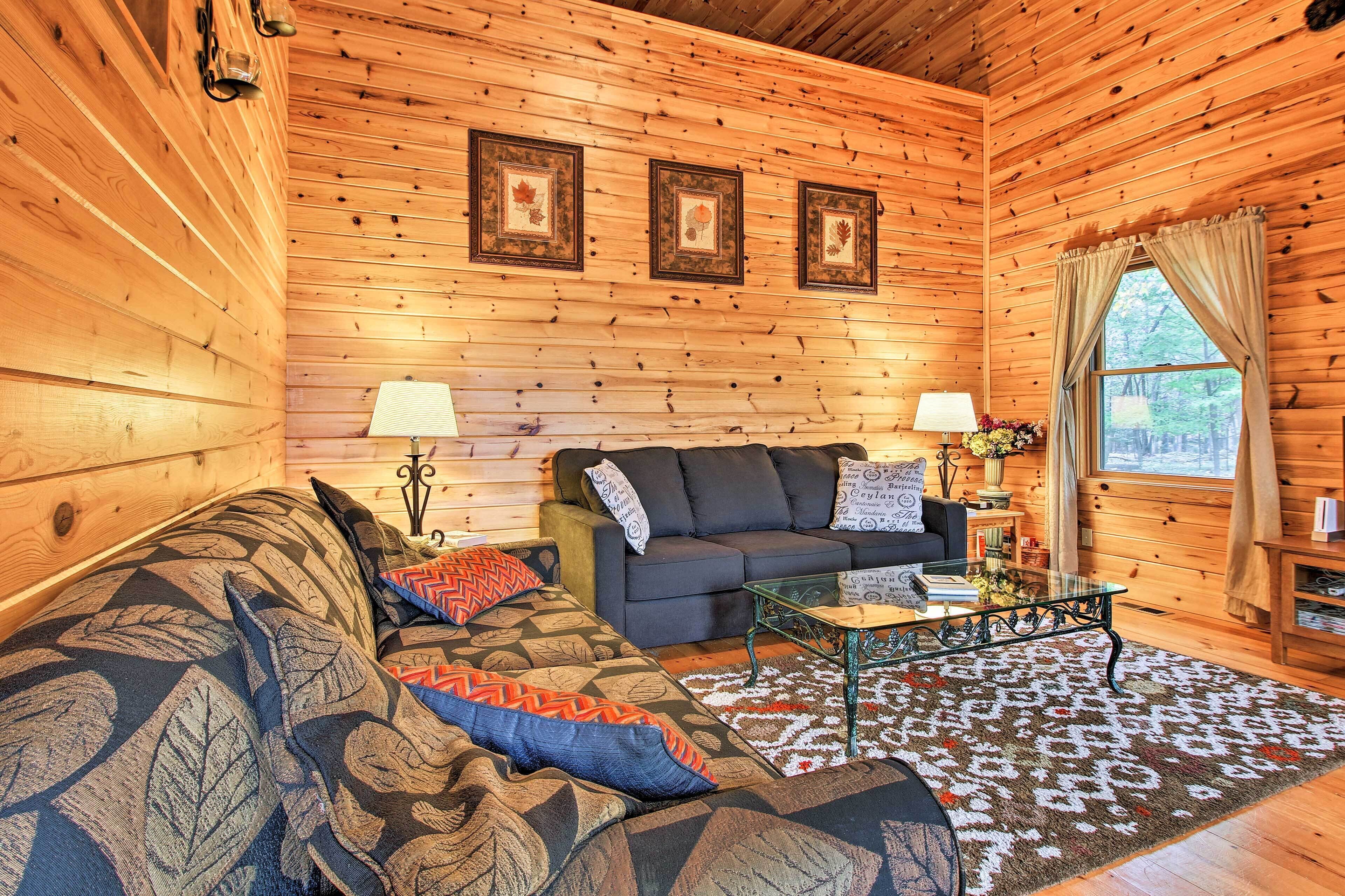 L’intérieur d’un chalet confortable, avec un canapé, une table basse et une lampe.