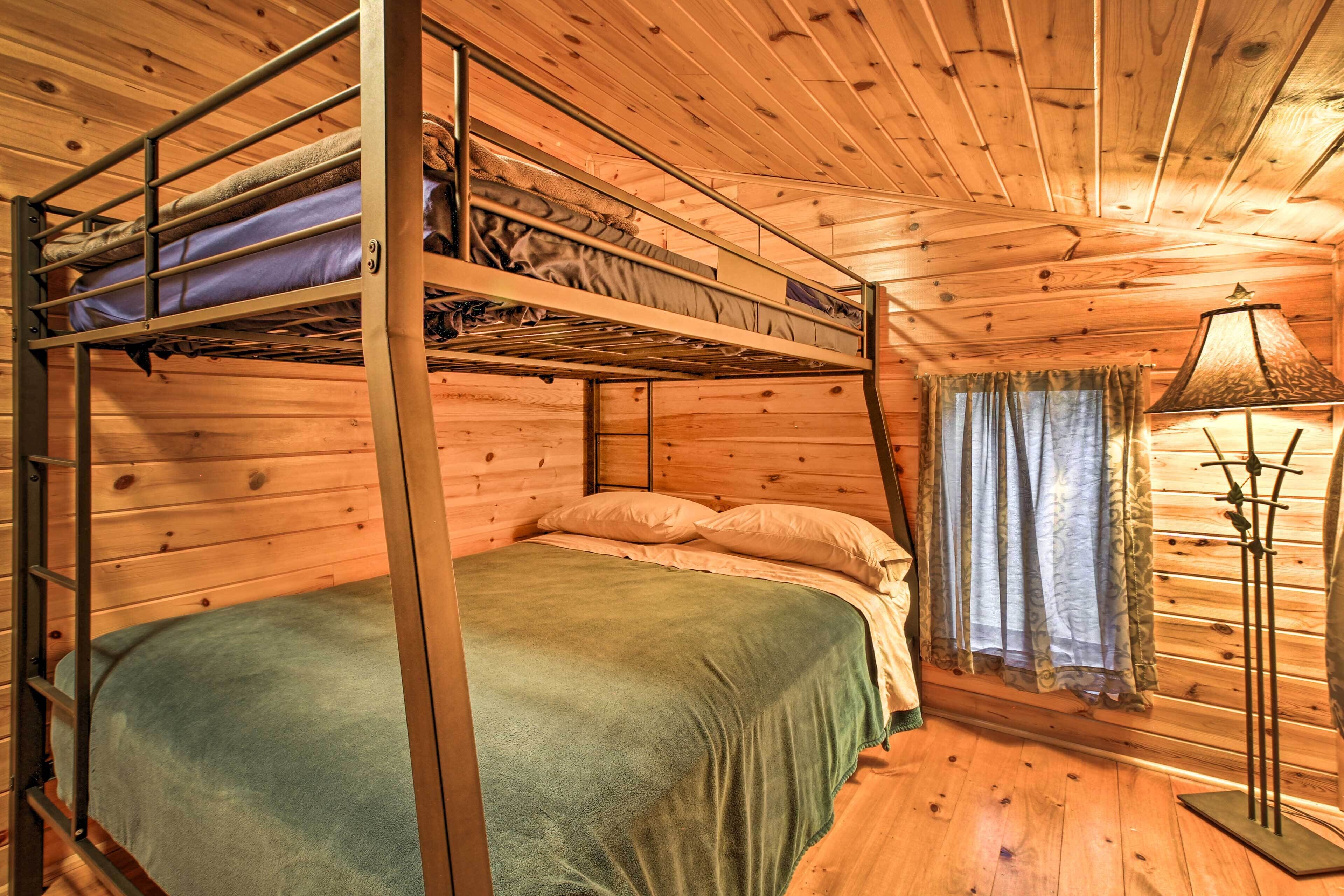 Dormitorio con literas, colcha verde, paredes de madera y una lámpara.