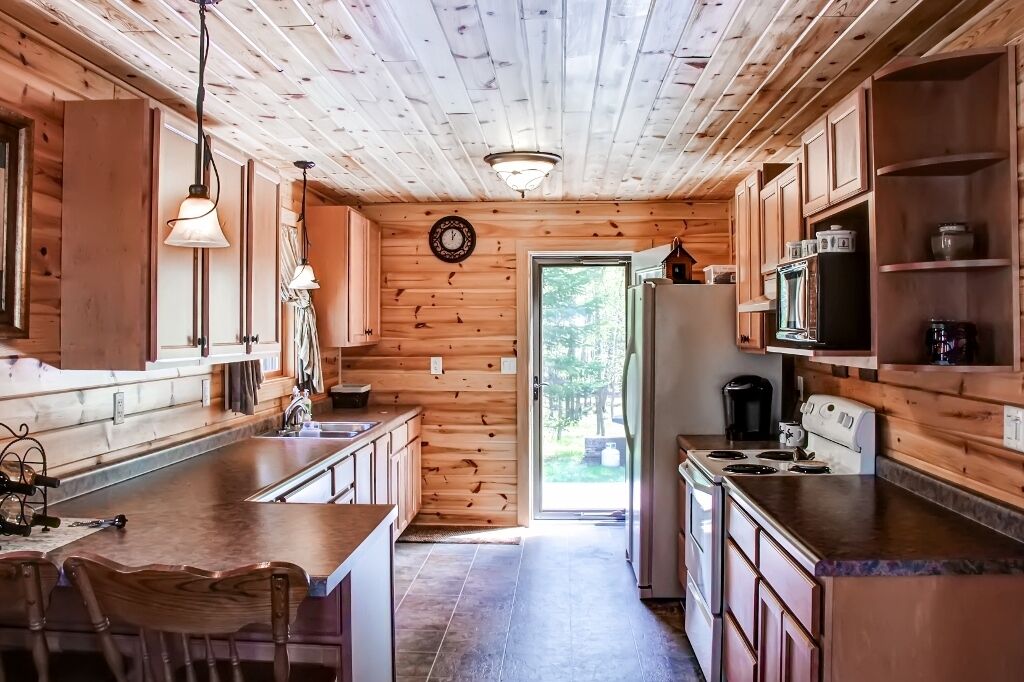 A wooden cabin kitchen with a central island, wooden cabinets, and a refrigerator.