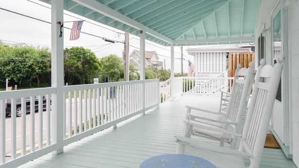 A covered porch with white railings and a blue table.