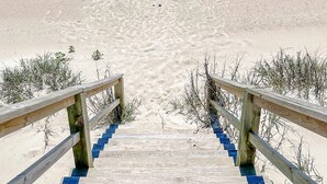 A wooden staircase leading to a beach with a clear view of the ocean. - Barnacle: Pet-Friendly Ocean Escape (Topsail Beach)