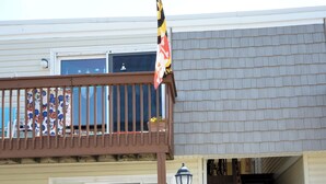 Un edificio de dos pisos con un balcón, una bandera y una escalera que lleva a un nivel superior.