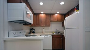 Una cocina con electrodomésticos blancos, armarios de madera y un lavavajillas.