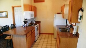 A compact kitchen with wooden cabinets, a central island, and a tiled floor. - OS756- 5 BRs, Private Pool, Hot Tub, Pool Table, Dog Friendly, Comm. Tennis! (Corolla)