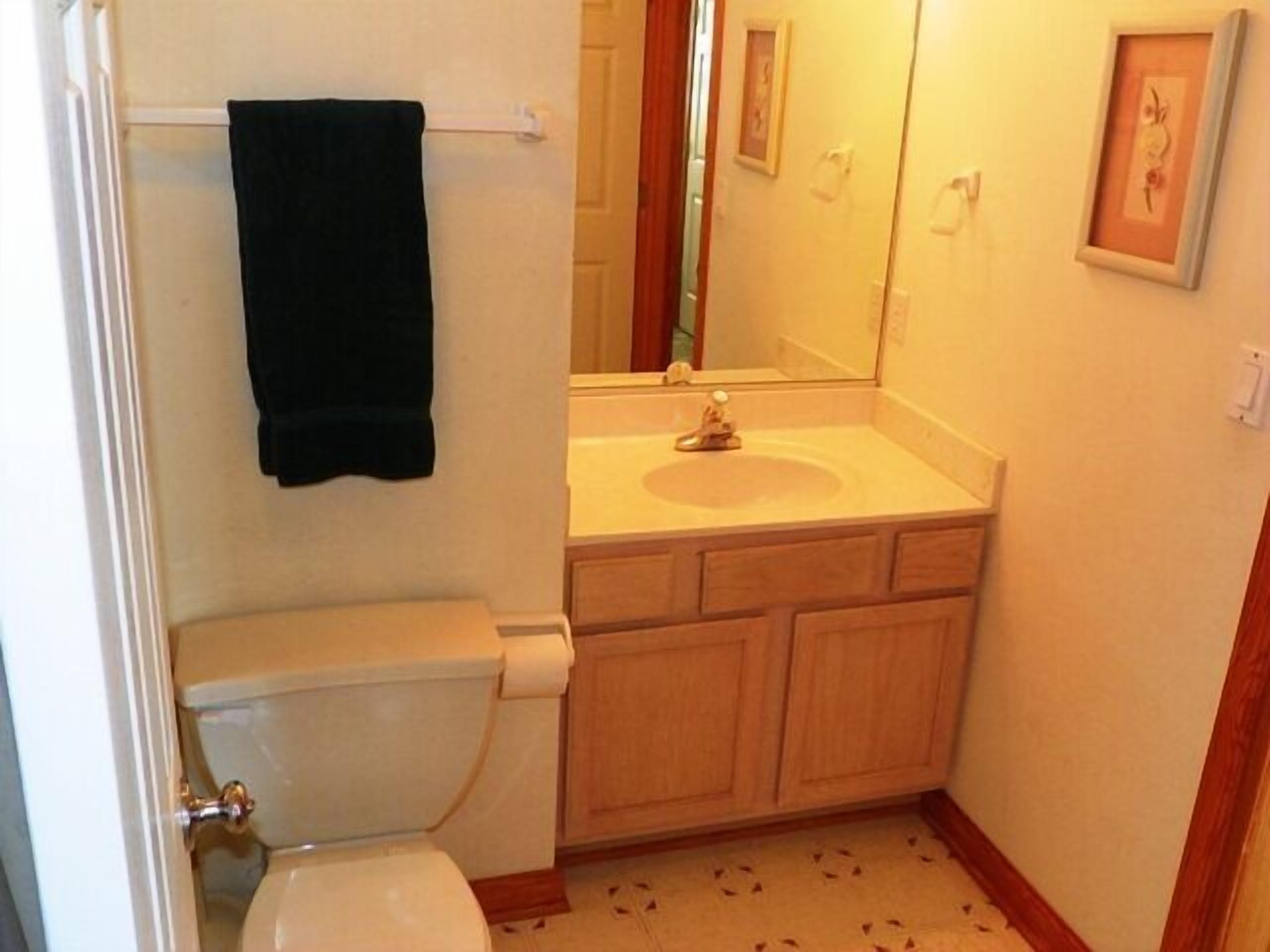 A small bathroom with a toilet, sink, and mirror.