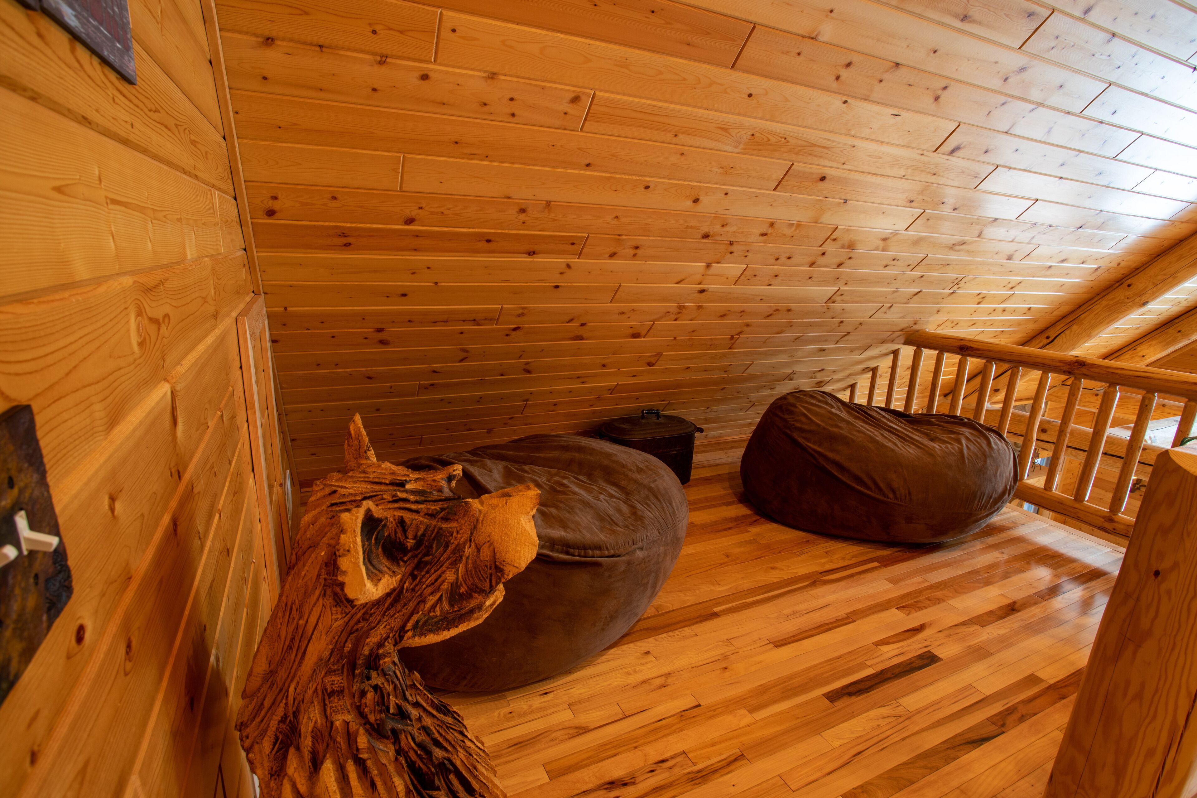 Een houten interieur met een schuine balkenplafond, een houten bank en een rustieke houten wand.