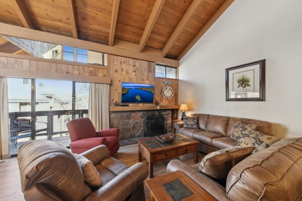 A cozy living room with leather sofas, a fireplace, and a television on the wall.