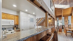 A kitchen with granite countertops, wooden cabinets, and a built-in microwave.