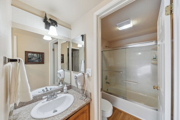 A bathroom with a sink, mirror, and shower.