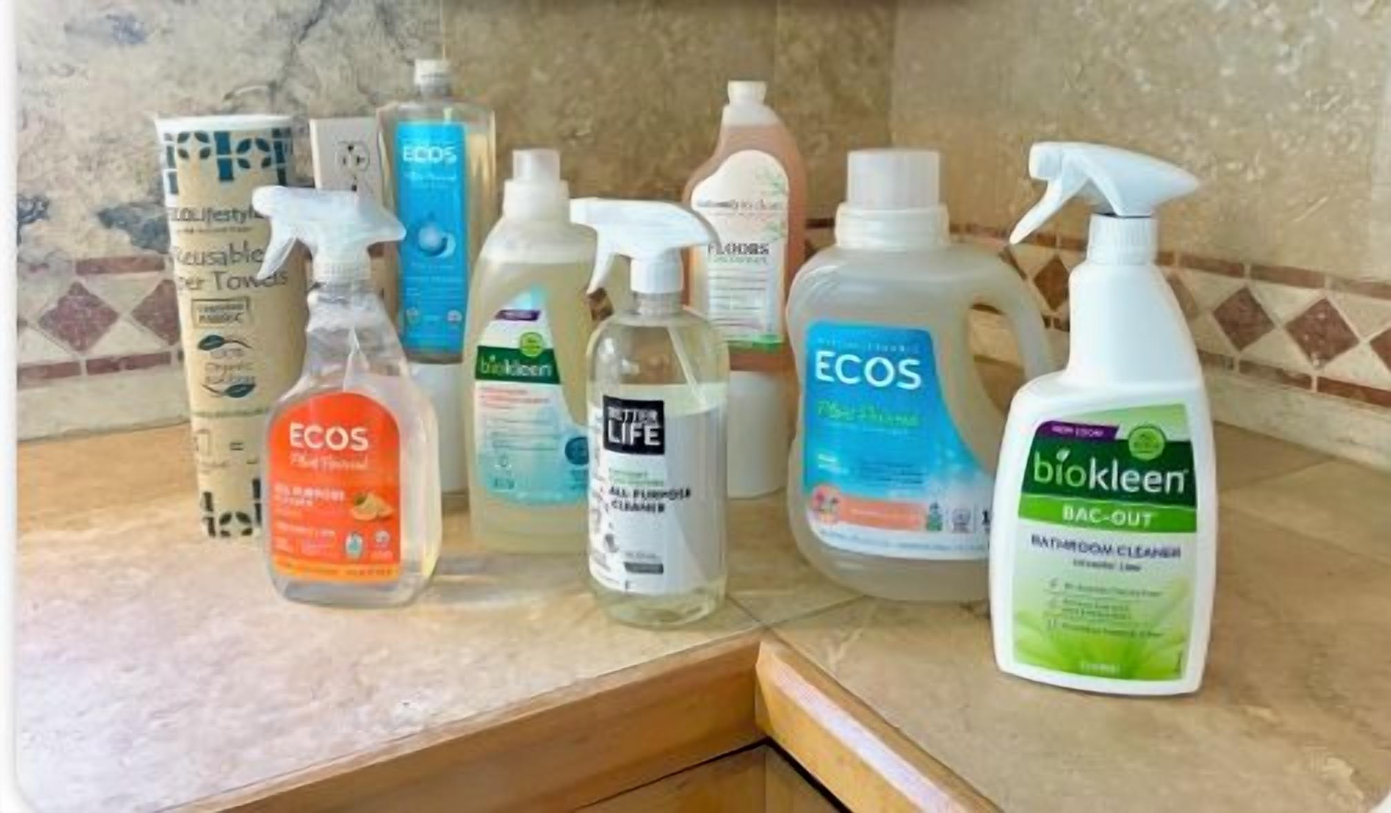 Un plan de travail sur lequel on trouve divers produits de nettoyage, notamment des bouteilles étiquetées « Ecos » et « Biokleen ».