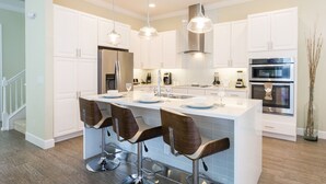 A modern kitchen with white cabinets, stainless steel appliances, and a central island with bar stools.