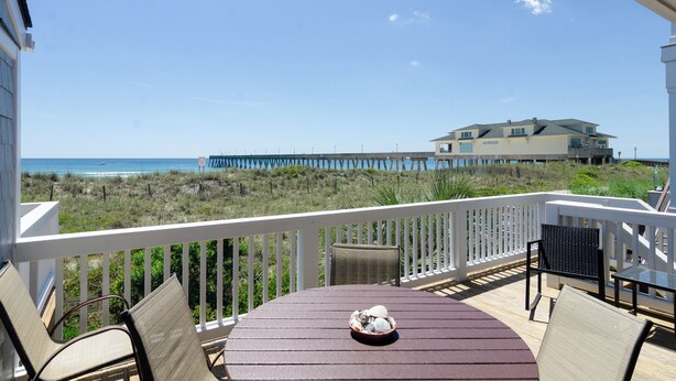A balcony with a view of the beach and a large house in the background. - 3BR Ocean Front Condo Near Johnnie Mercer’s! (Wrightsville Beach)