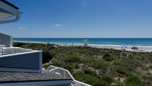 A beachfront view from a balcony with a clear sky, a sandy beach, and a lifeguard tower. - 3BR Ocean Front Condo Near Johnnie Mercer’s! (Wrightsville Beach)