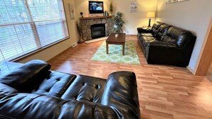 A living room with a fireplace, leather sofa, and a television. - Whistling Brook @ Spring Brook Resort (Wisconsin Dells)