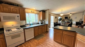 A kitchen with wooden cabinets, a microwave, a stove, and a sink. - Whistling Brook @ Spring Brook Resort (Wisconsin Dells)