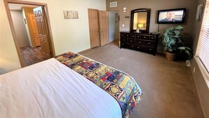 A bedroom with a bed, dresser, television, and a potted plant. - Whistling Brook @ Spring Brook Resort (Wisconsin Dells)