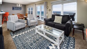 A living room with a glass coffee table, grey and black sofas, and a patterned rug.