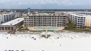 Un hotel frente a la playa con piscina, sombrillas y un tanque de agua.