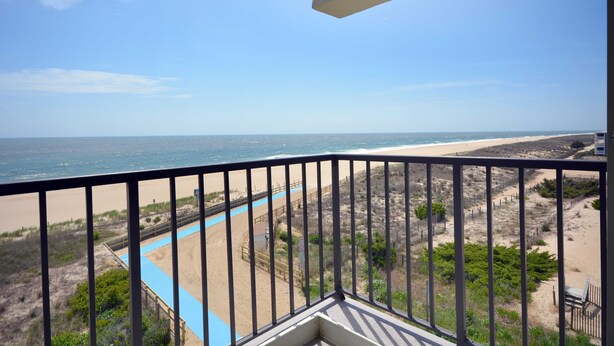 Un balcon avec vue sur une plage et l’océan.