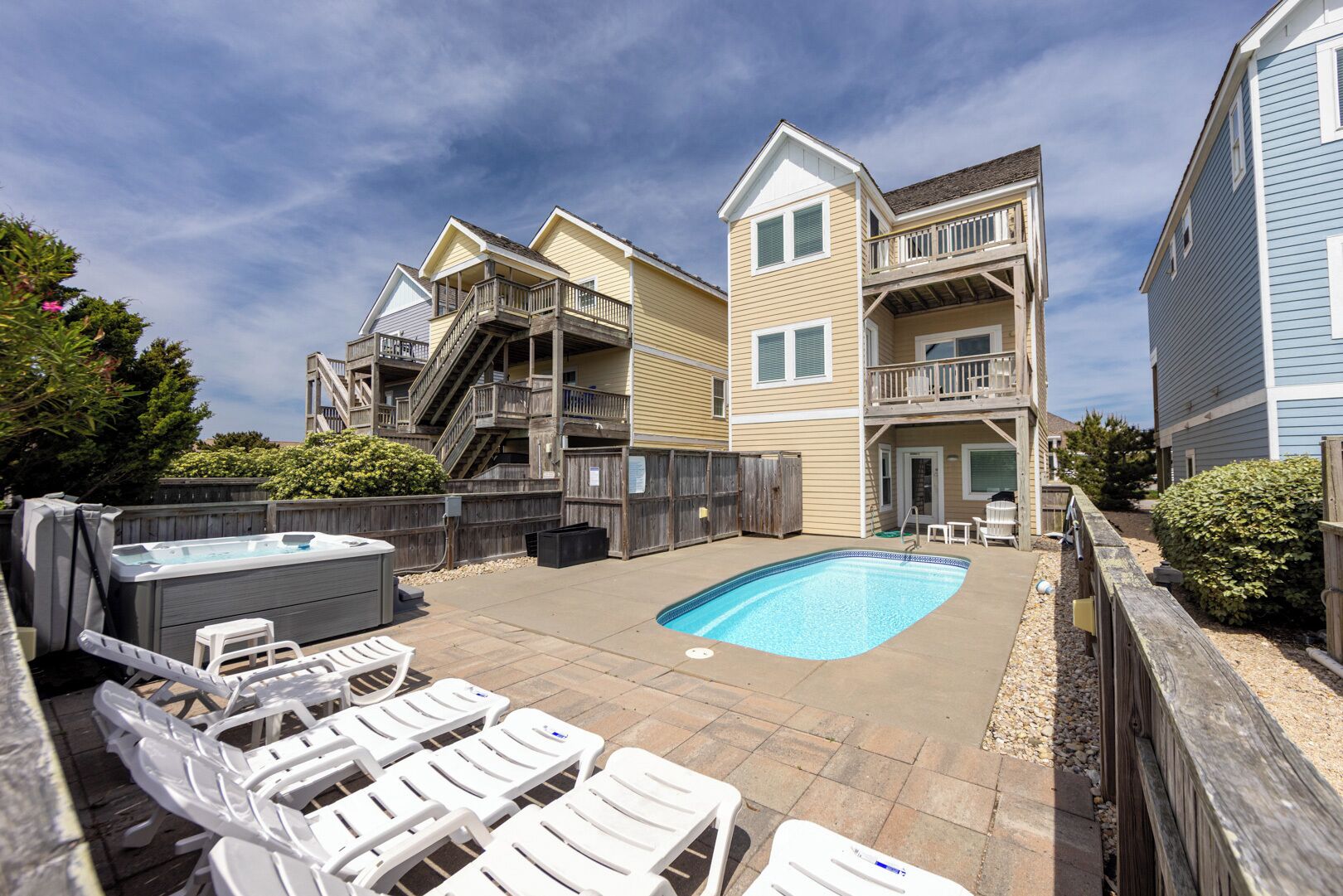 A residential area with a swimming pool, lounge chairs, and a hot tub.