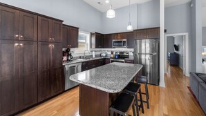 A modern kitchen with dark wood cabinets, stainless steel appliances, and a granite countertop. - Pier Pressure At SandCastle Nags Head Village, Private Pool, On the Golf Course (Nags Head)