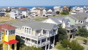 A residential area with multi-story houses, a visible road, and a clear view of the ocean. - Mayflower - Corolla, Ocean Sands, 250 Yds to Beach, Lake View, Pool, Hot Tub, Flex Stays (Corolla)