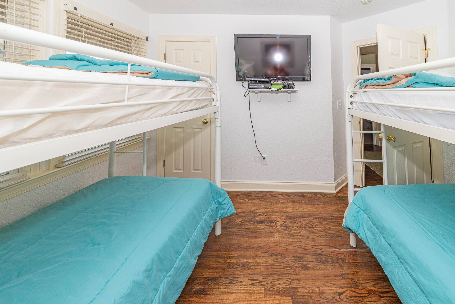 Ein Zimmer mit zwei Etagenbetten, einem an der Wand befestigten Fernseher und einer Tür zu einem Schrank.