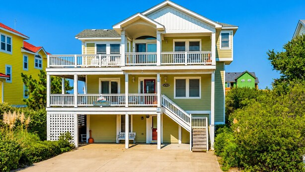 A two-story house with a balcony, a front porch, and a visible address number. - Mayflower - Corolla, Ocean Sands, 250 Yds to Beach, Lake View, Pool, Hot Tub, Flex Stays (Corolla)