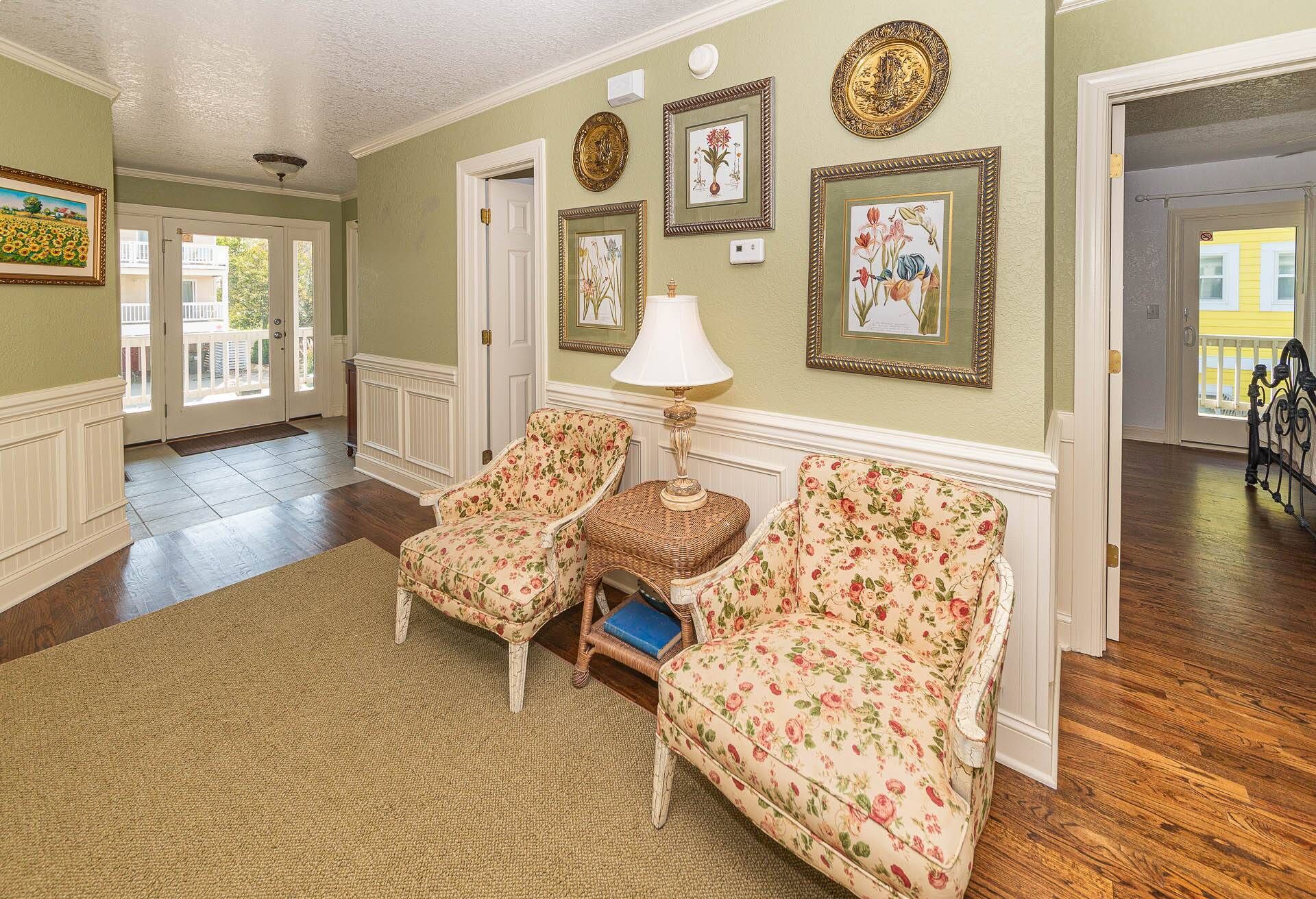 A spacious living room with floral-patterned sofas, a wicker side table, and a floor lamp.