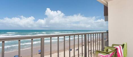 A balcony with a view of the beach and ocean.