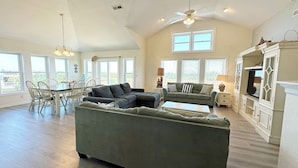 En rummelig opholdsstue med en stor hjørnesofa, et spiseområde med stole og en pejs.