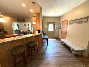 A kitchen with wooden bar stools, a bench, and a dining table.