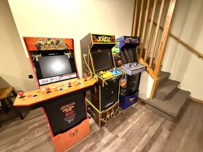Uma escadaria com máquinas de fliperama, incluindo os jogos 'Golden Axe' e 'Joust'.