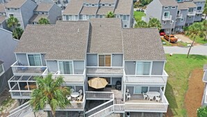 Ein mehrstöckiges Wohngebäude mit Balkonen, einer kleinen Terrasse mit Gartenmöbeln und Blick auf die umliegende Nachbarschaft.