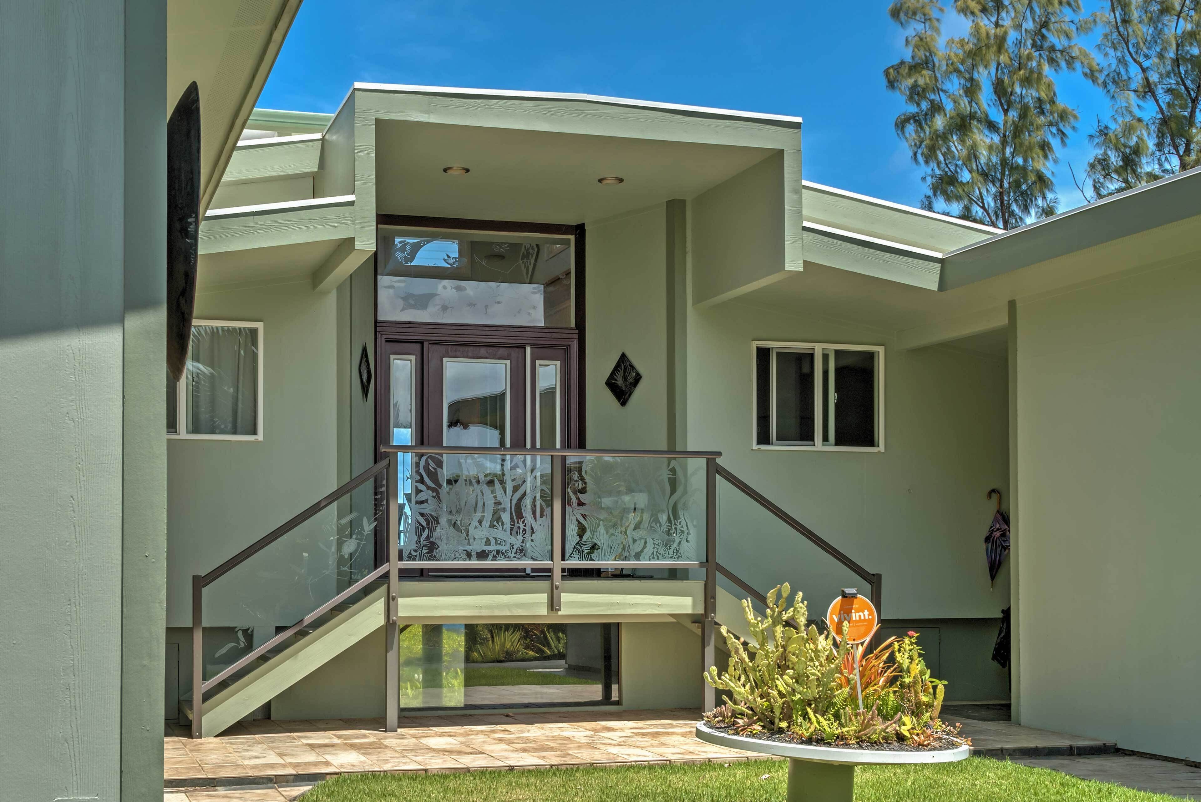 A modern house with a balcony, a staircase, and a small garden area.