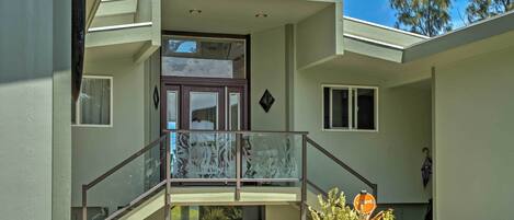 A modern house with a balcony, a staircase, and a small garden area.