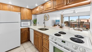 Una cocina moderna con armarios de madera, un refrigerador blanco, un microondas, un fregadero y una estufa.