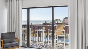 Un balcón con vista al océano, una silla y una mesa.