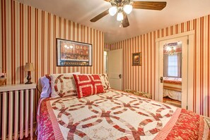 A bedroom with striped wallpaper, a quilted bedspread, a ceiling fan, and a framed picture on the wall. - Whimsical Lancaster Home - 4 Mi to Sight & Sound (Lancaster)