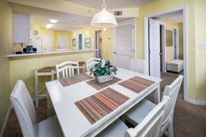 Enjoy meals in this inviting dining area with a table set for four, featuring colorful placemats and a beautiful bouquet.