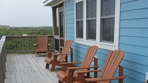 A blue house with a wooden deck and four Adirondack chairs. - Summer Paws | 3BR 4x4 OBX | Hot Tub | Pets | 4 night stay available for fall (Carova)