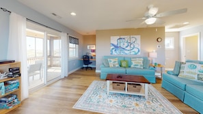 A spacious living room with a blue sofa, a coffee table, and a ceiling fan.