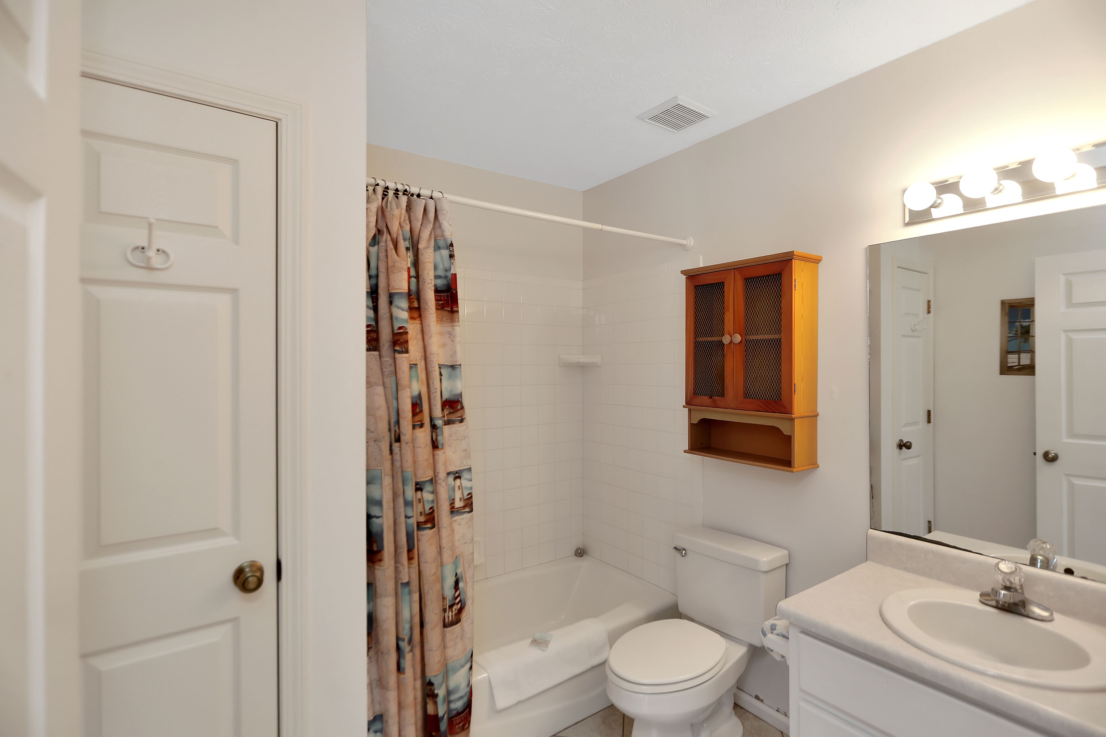 A bathroom with a bathtub, toilet, and vanity with a mirror.