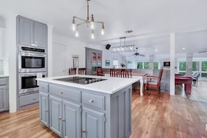 A modern kitchen with a central island, built-in ovens, and a dining area with a view.