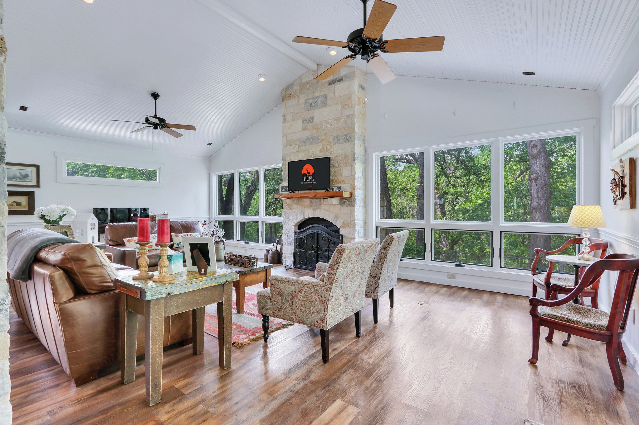 Una sala de estar amplia con chimenea, ventanas grandes y ventilador de techo.