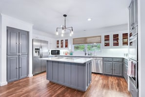 A modern kitchen with a central island, stainless steel appliances, and a view to the outdoors.