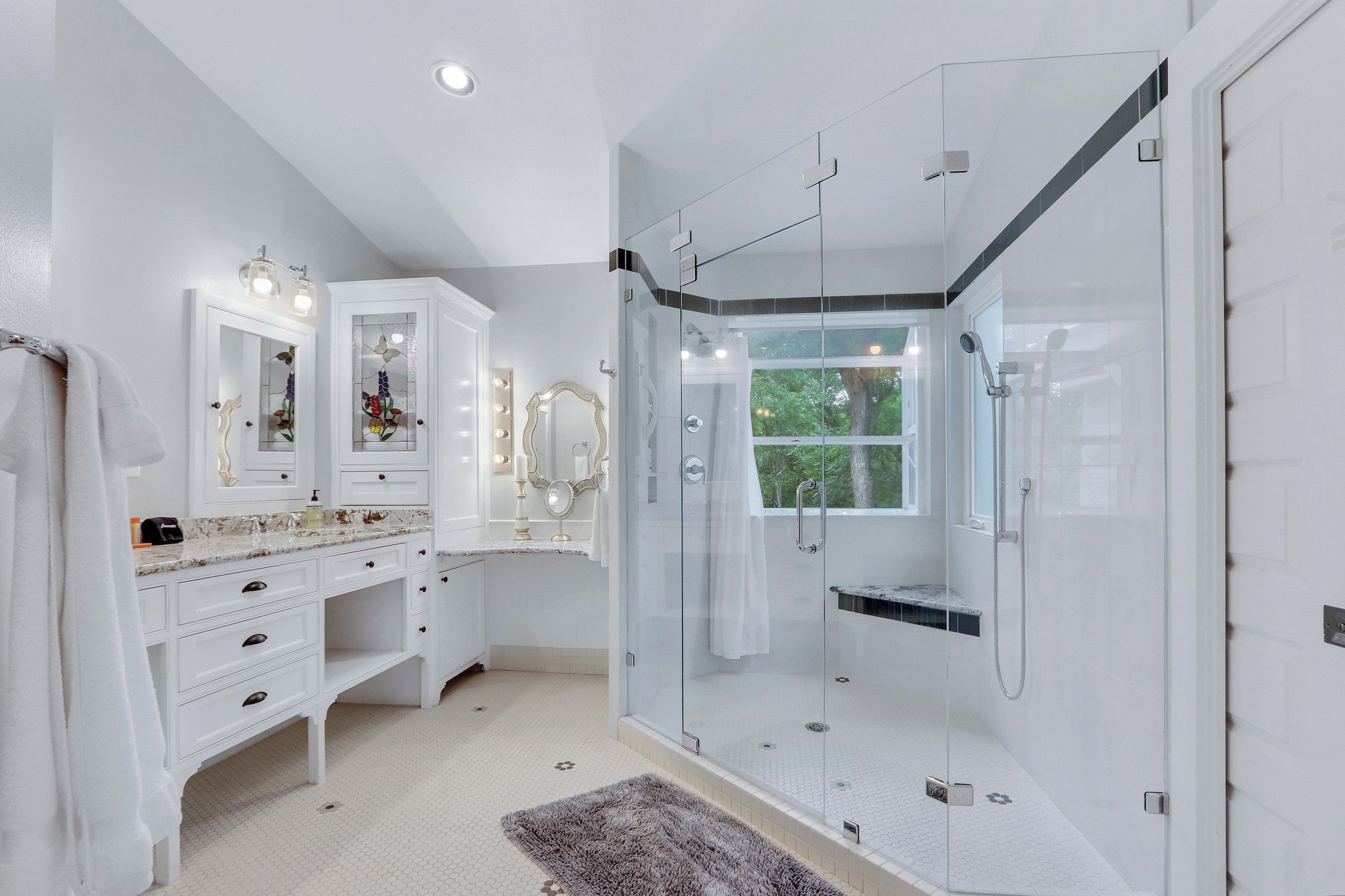 A modern bathroom with a glass-enclosed shower, white cabinetry, and a vanity with a mirror.