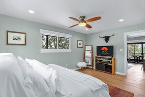 Un dormitorio con cama, ventilador de techo, televisor y decoración de cráneo de toro.