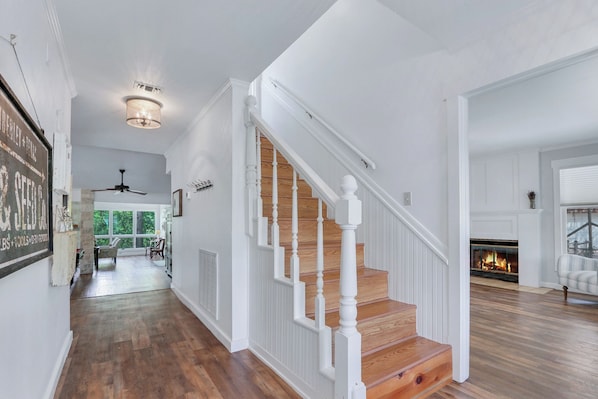 A spacious living area with a wooden staircase, a fireplace, and a dining area with natural light.