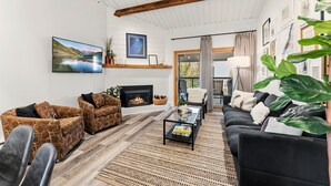 A living room with a fireplace, a television, and a sofa. - Luxury Ski-In Condo | 2023 Remodel | Walk to Peak 9 Lift and Mountain Views (Breckenridge)